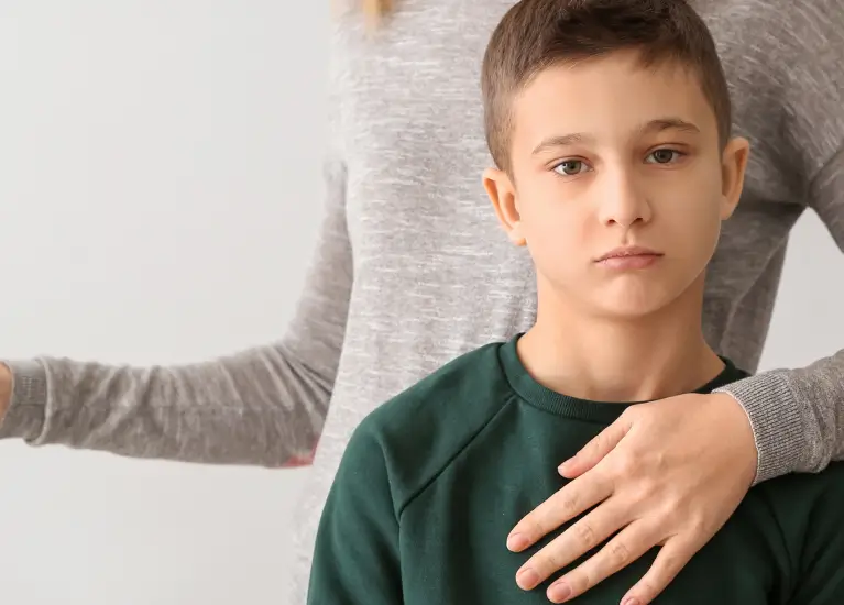 A woman holding a hand on a boy's chest
