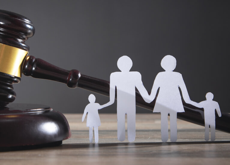 A close up of a gavel and paper cut out of a family