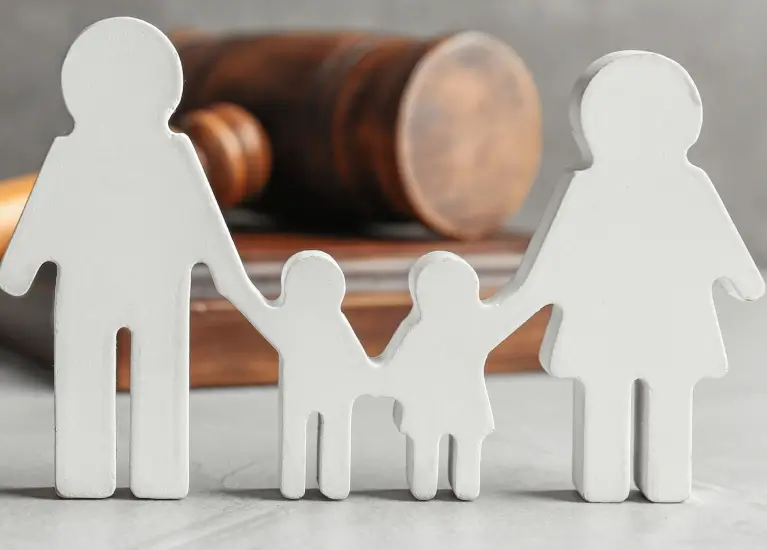 A close up of a gavel and paper cut out of a family